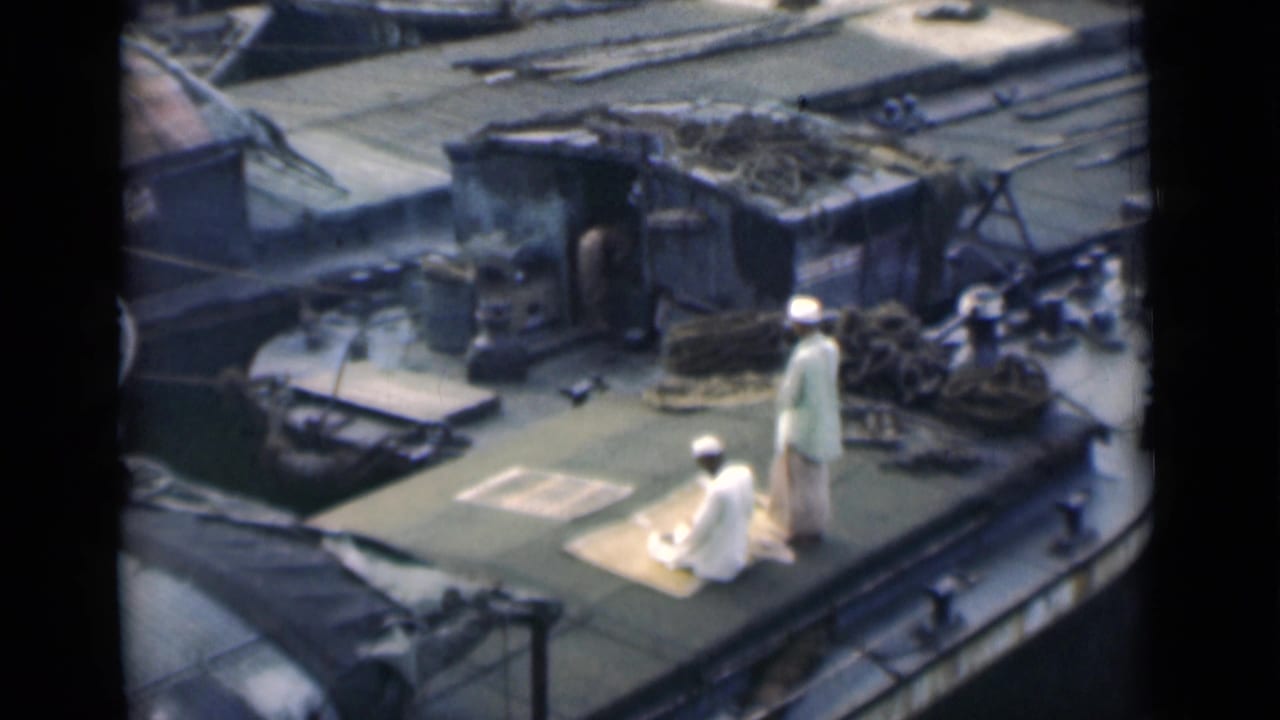 1946 Calcutta rooftop scene with one Muslim man kneeling on a prayer mat and another standing close by in white clothing.
