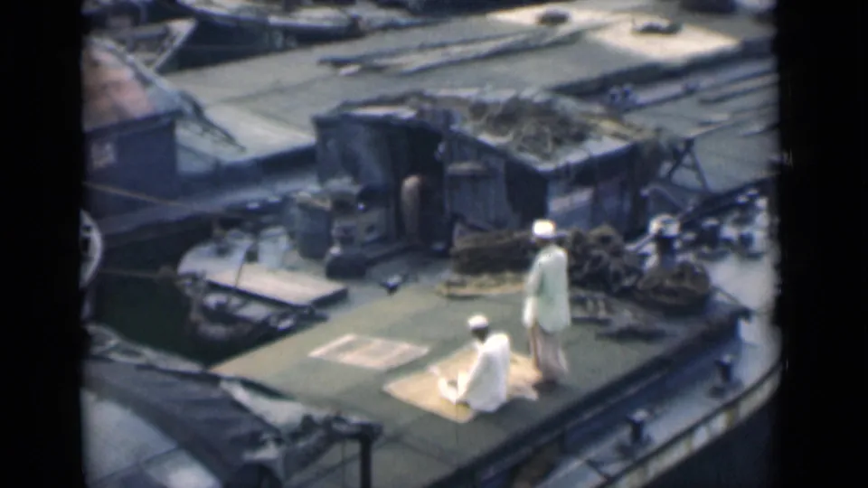 The final frame holds on the two men in white clothing on the 1946 Calcutta boat deck, surrounded by ropes, cargo, and railings.