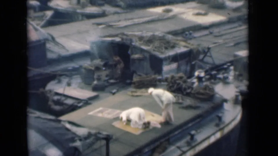 The final frame keeps the high-angle view of two men on a Calcutta boat deck, with prayer continuing beside ropes and deck equipment.
