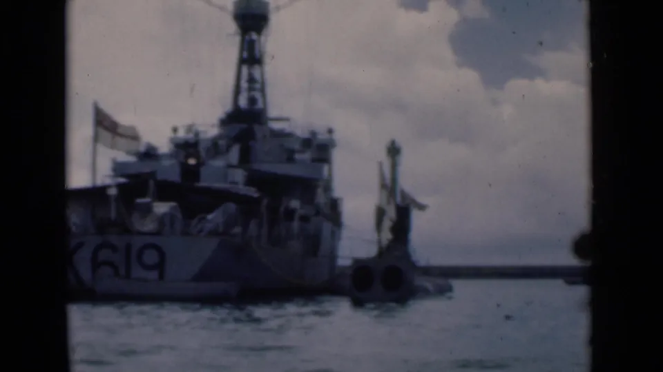 Close harbor view of the vessel stern marked K619, with flags, rigging, water, and dockside equipment in Colombo.