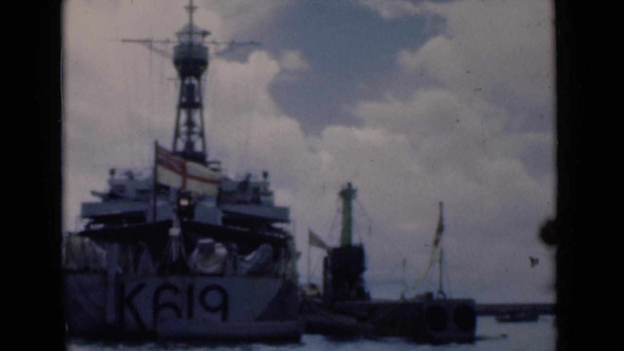 Naval vessel marked K619 beside a harbor quay under cloudy sky.