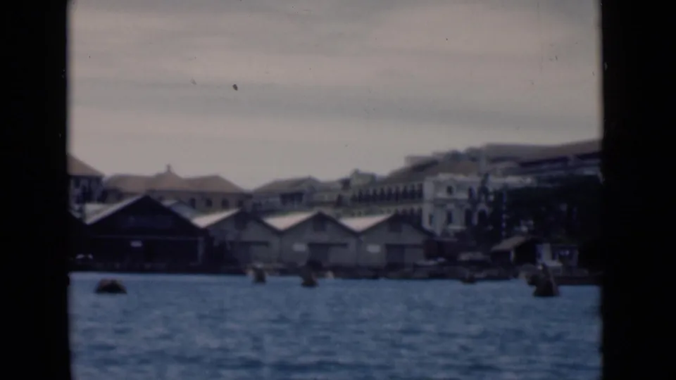 Colombo harbor in 1946 with low waterfront sheds, colonial-era buildings, small craft, and buoys across the water.