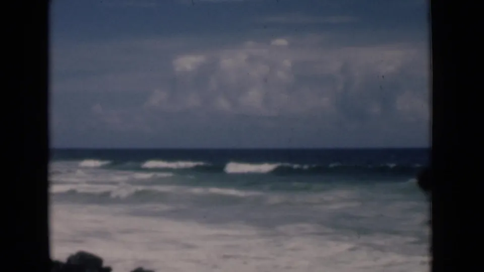 1946 Colombo, Ceylon coastal view with white surf lines, blue-green water, cloudy sky, and visible 8mm frame borders.