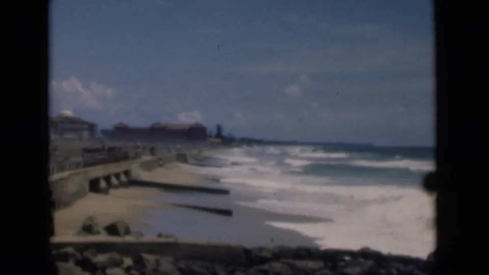 Colombo shoreline in 1946, showing foamy surf, a sandy beach, seawall structures, and low buildings under a bright sky.