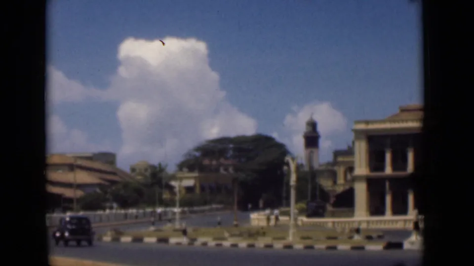 A 1946 Colombo street view shows a dark car near railings, a clock tower, trees, and the edge of a columned building.