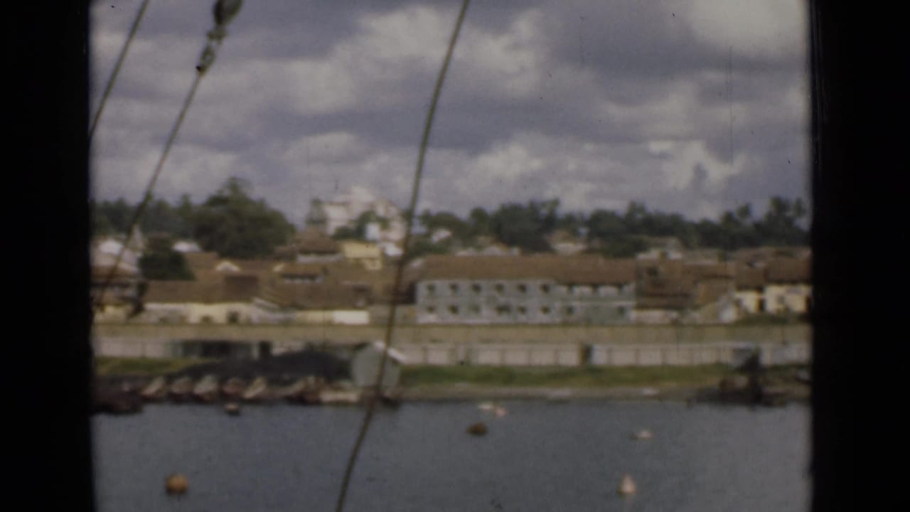Colombo waterfront seen from the water in 1946, with a quay, pale buildings, tiled roofs, and rigging in front.