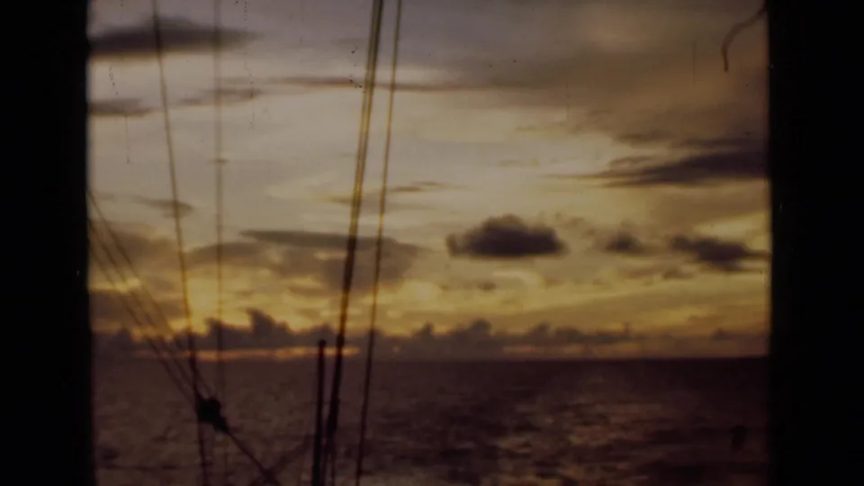 The clip ends with a golden sunset over the sea, seen from the ship with rigging and cables silhouetted in the foreground.