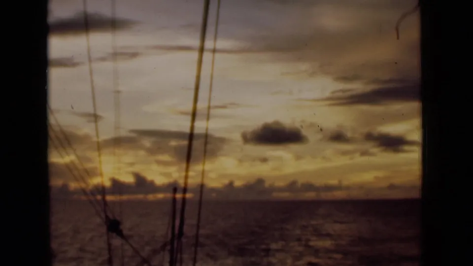 1946 Colombo, Ceylon home-movie frame showing a dusk ocean horizon through dark sailing rigging.