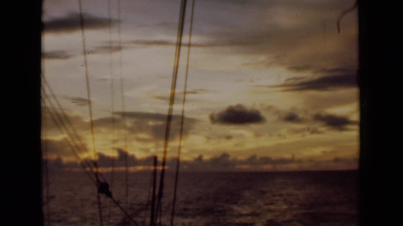 Golden sunset sky over water framed by vertical rigging lines.