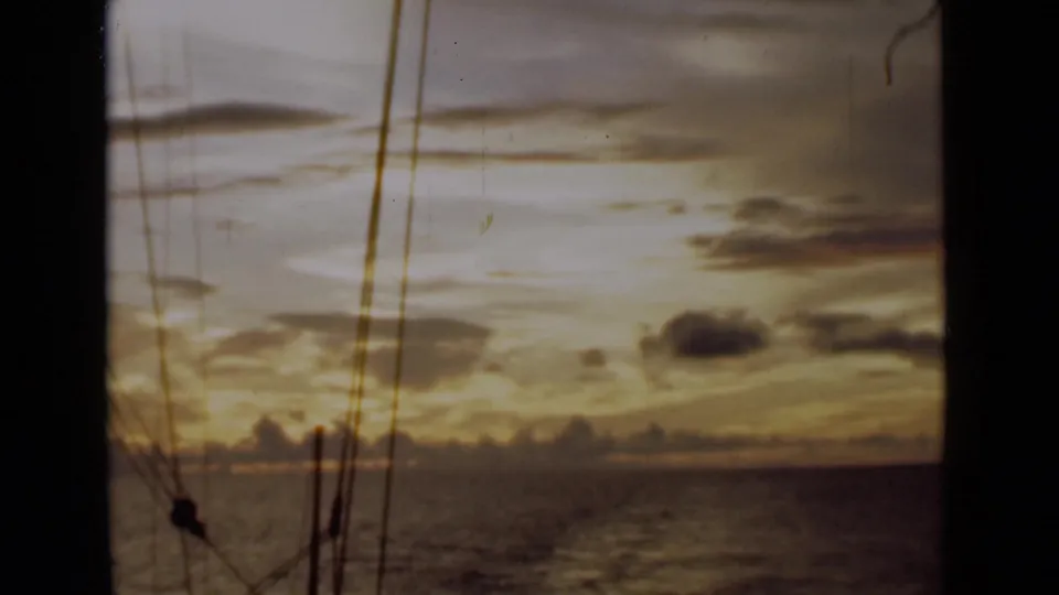 Aboard a sailing boat near Colombo in 1946, the frame shows golden dusk light, scattered clouds, and rigging over the ocean.
