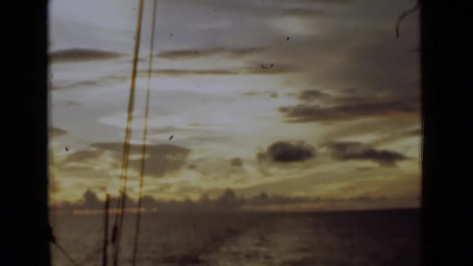 End frame of 1946 Colombo sailing footage, with muted sunset color, open water, distant clouds, and rigging in the foreground.
