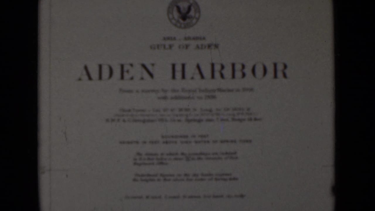 Printed title card reading Aden Harbor, framed by dark film edges.