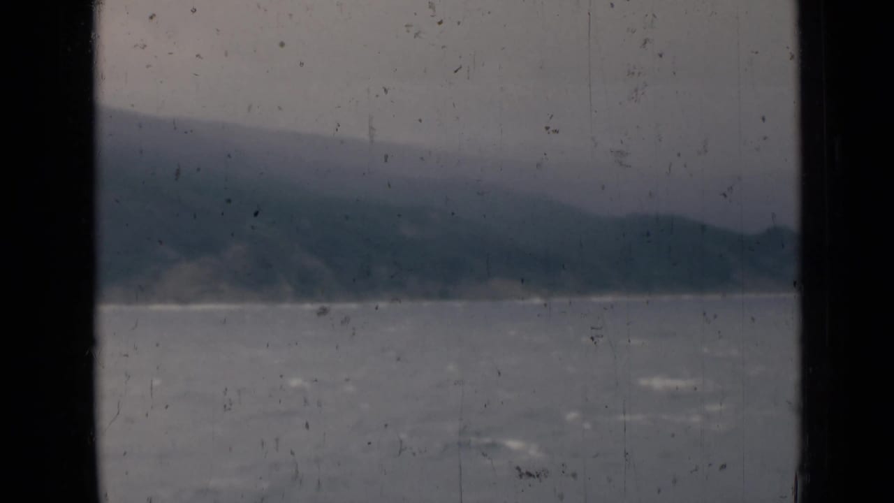Grey water and distant shoreline behind a central dark frame bar.