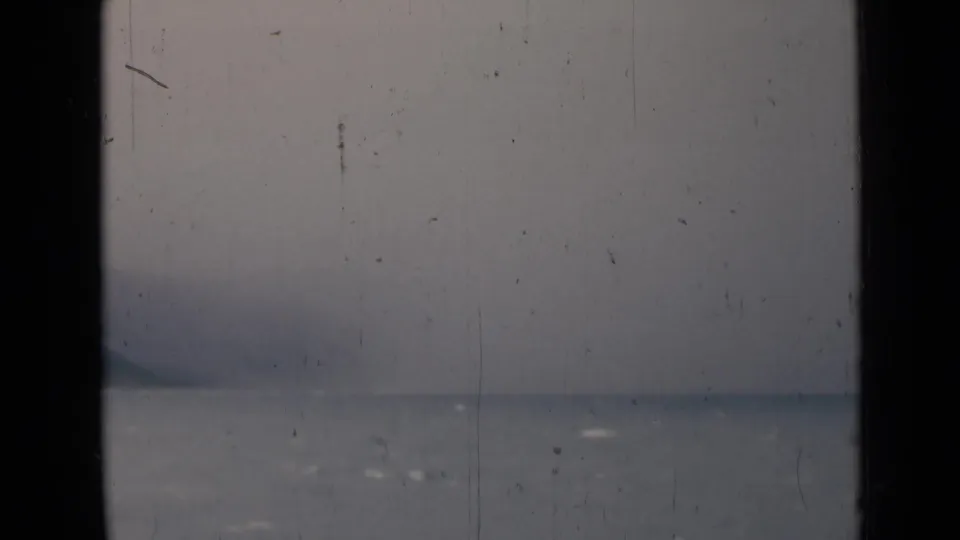 1946 India home-movie view of a distant headland and grey sea, split by a dark window-like vertical bar.
