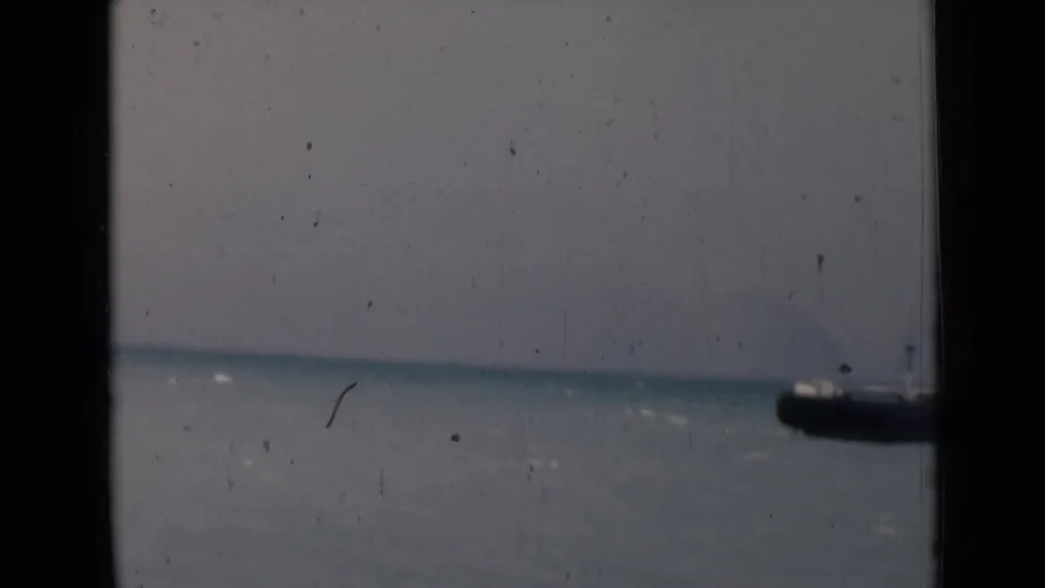 1946 India 8mm frame with a distant ship on the right side of a calm sea, seen through dark vertical framing.