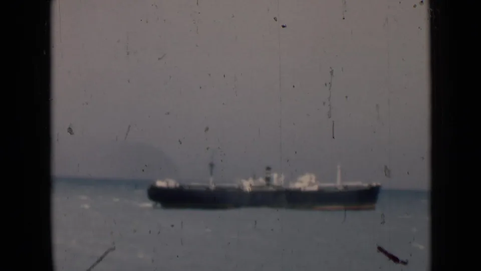 1946 India home-movie frame of a cargo vessel crossing the water, with soft focus and visible film dust.