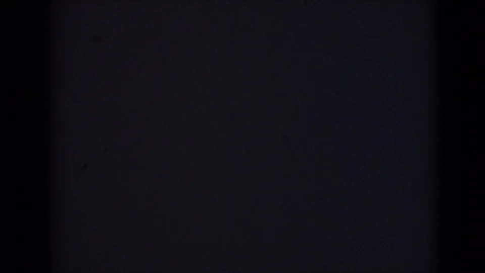 Dark 8mm frame from the 1946 India clip, with faint exposure separation, grain, and shadowed gate edges.
