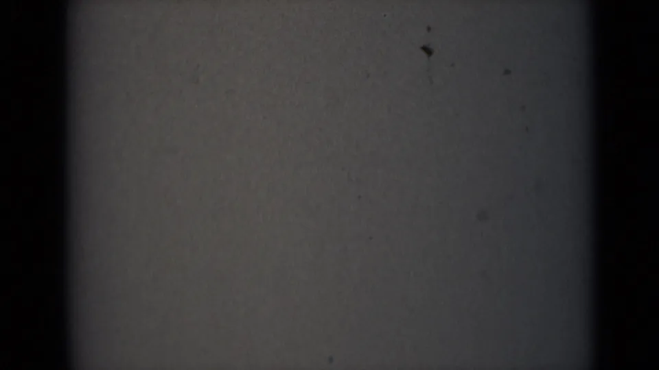 India 1946 8mm frame with dark vertical borders, a gray-brown field, scattered black spots, and visible film grain.