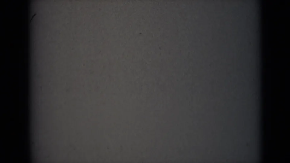1946 India 8mm reel opening frame showing dim grey film surface, gate shadow, dust specks, and faint scratch marks.