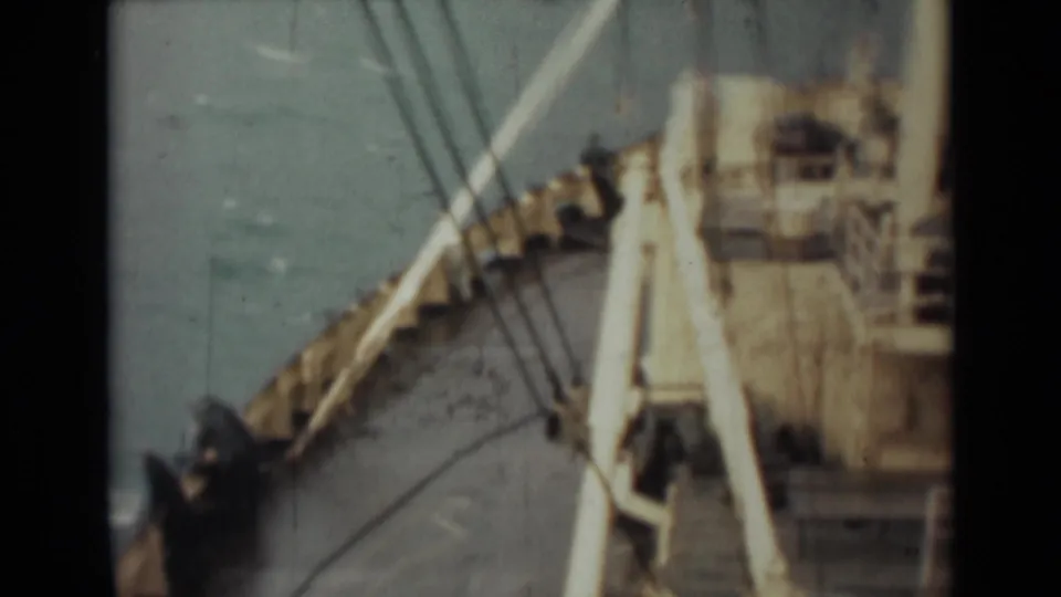 Shipboard 8mm frame from 1946 India showing the bow area, deck railings, rigging lines, pale superstructure, and open water beyond.