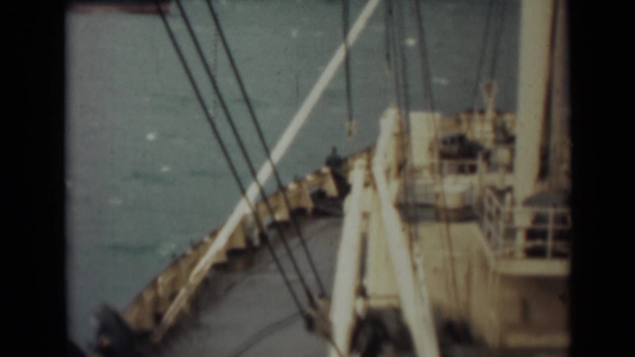 1946 India home-movie frame showing ship deck structures and rigging above open water from a vessel at sea.