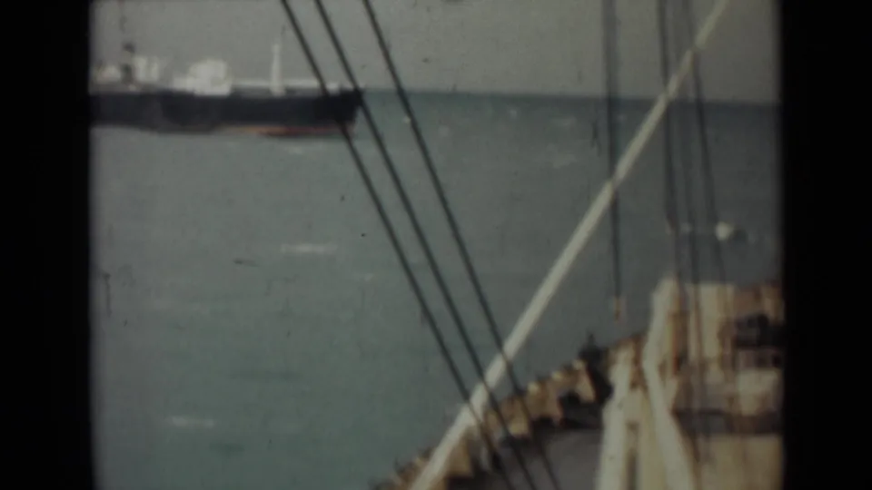 1946 India maritime footage with ship rigging in the foreground and a distant cargo vessel across the sea.