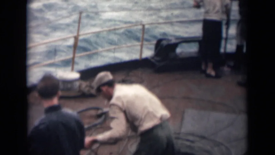1946 India home-movie frame of men in work clothes handling lines on a ship deck at sea.