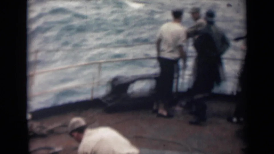 1946 India shipboard frame with several people near the rail and one man working over rope in the foreground.
