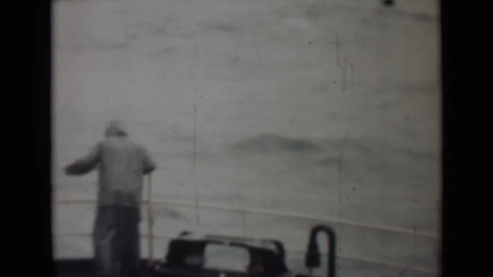 In this 1946 India 8mm frame, a man stands on a boat deck railing and looks toward choppy open water.