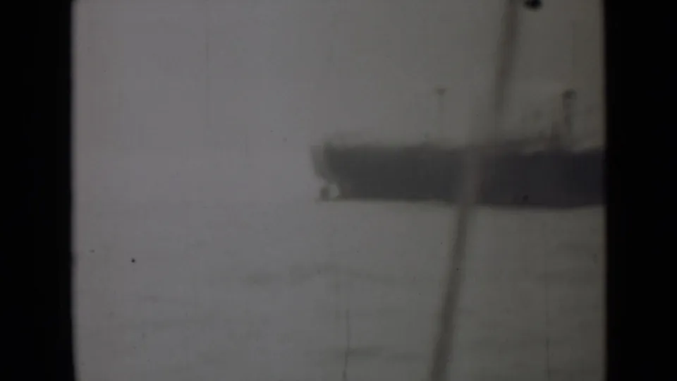 A distant vessel appears across pale water in a soft black-and-white 8mm frame from the India 1946 clip.