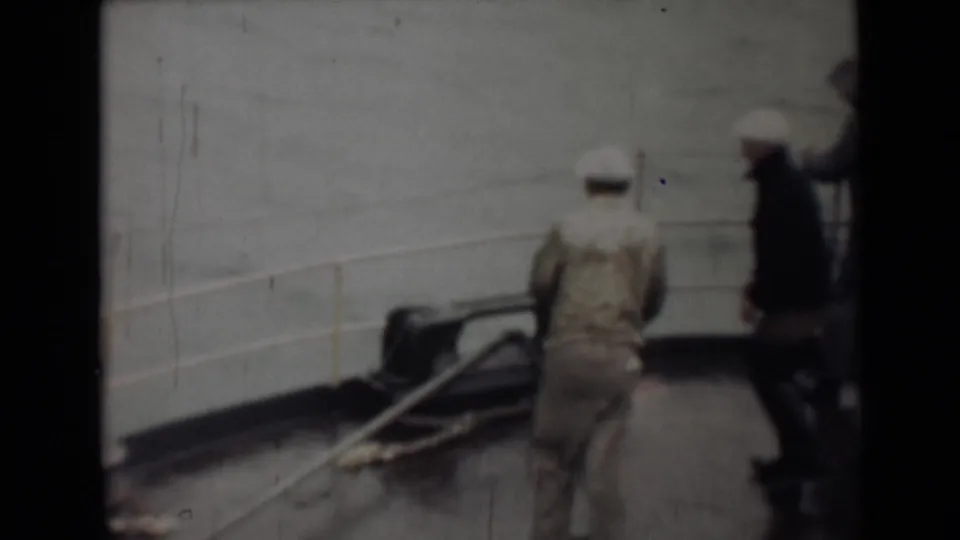 In supported 1946 India home-movie footage, a man in light clothing moves along a deck beside railings and dark mooring equipment.