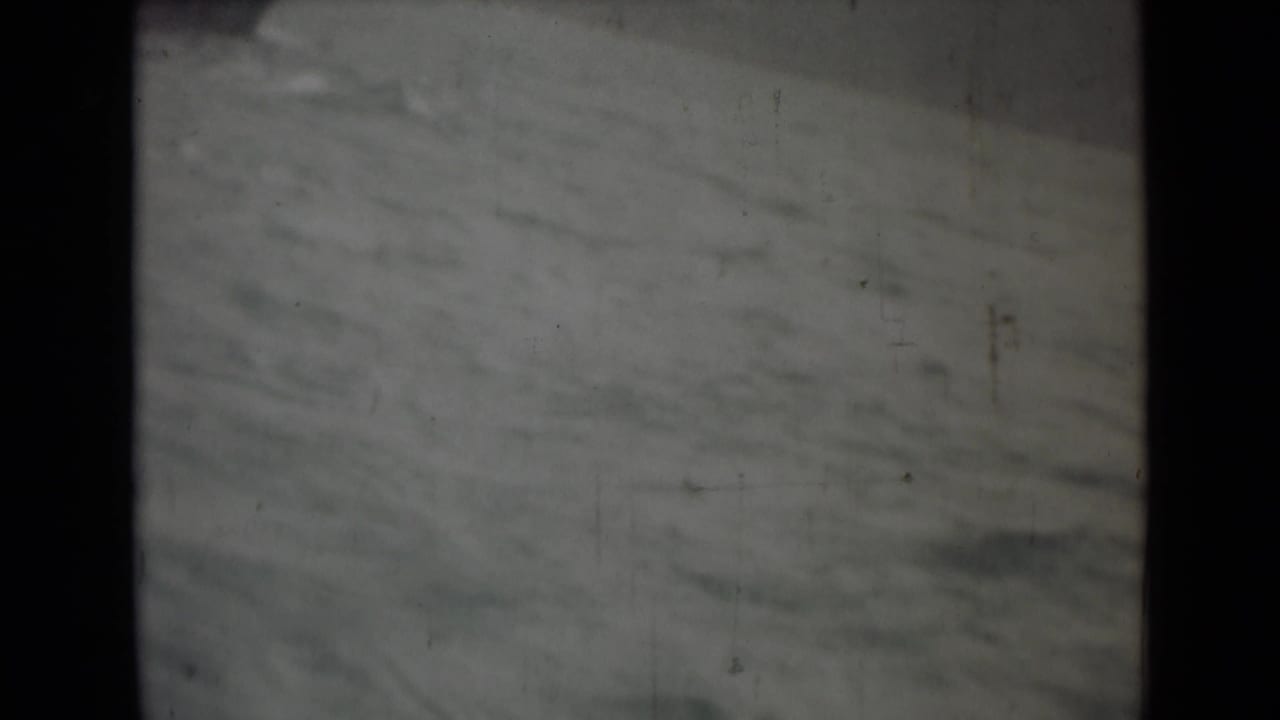 1946 India 8mm frame showing rough water and a small distant dark shape near the bottom of the shot.