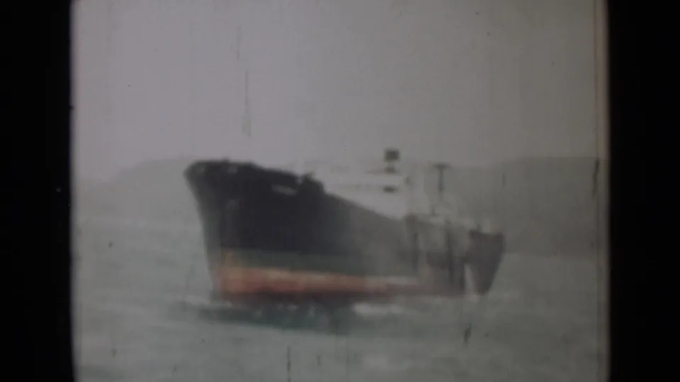 1946 India 8mm frame of the cargo ship moving through gray-green water with soft focus and visible film wear.