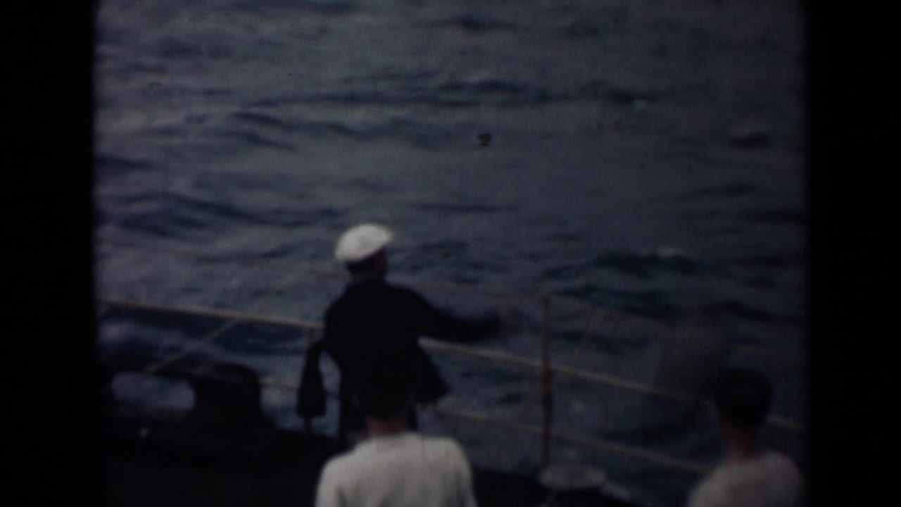 1946 India 8mm deck view with a crew member in a white cap by the railing and dark water beyond.