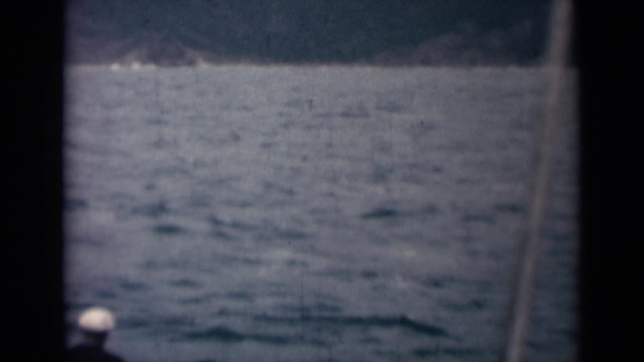 Open water framed by dark ship structure, with a small white cap near the lower left.