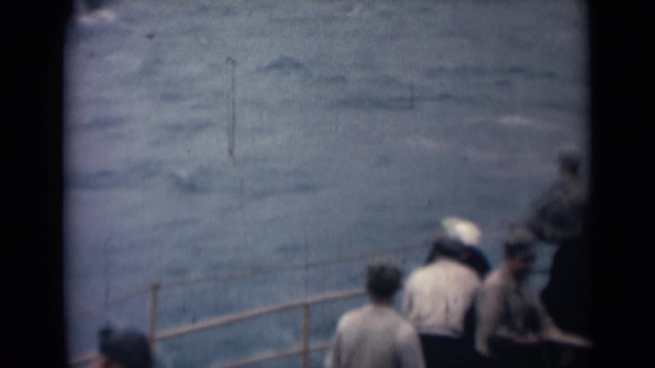 1946 India home-movie frame with people near a boat railing, some partly cropped, looking out over choppy blue water.