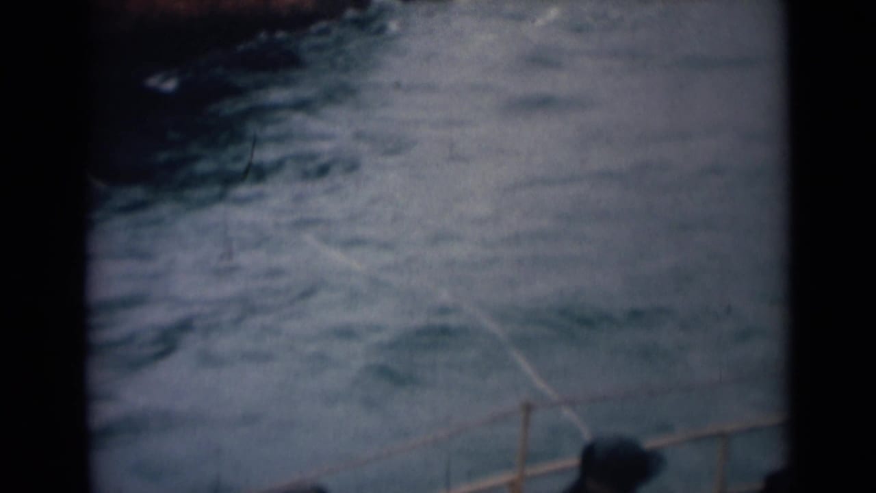 Soft 8mm frame from the 1946 India boat scene showing choppy water and a small section of railing at the bottom of the view.