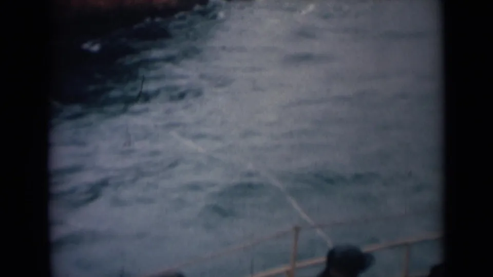 Soft 8mm frame from the 1946 India boat scene showing choppy water and a small section of railing at the bottom of the view.