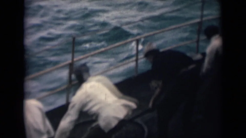 India 1946 8mm frame showing men on a boat deck working near railings as choppy water surrounds the vessel.