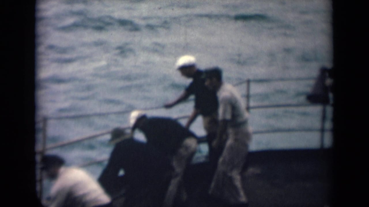 India 1946 8mm frame showing deck labor on a boat, with men near a rope and railings against rough sea.