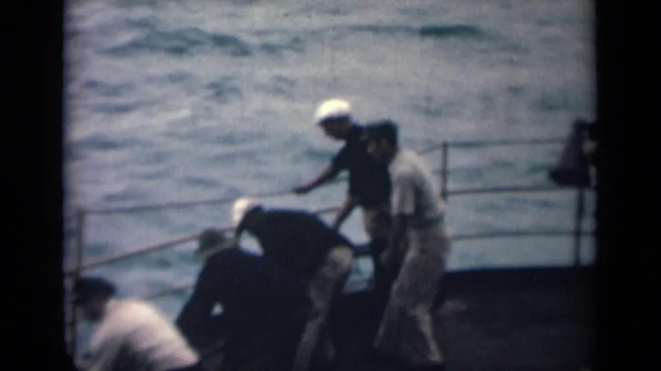 India 1946 8mm frame showing deck labor on a boat, with men near a rope and railings against rough sea.
