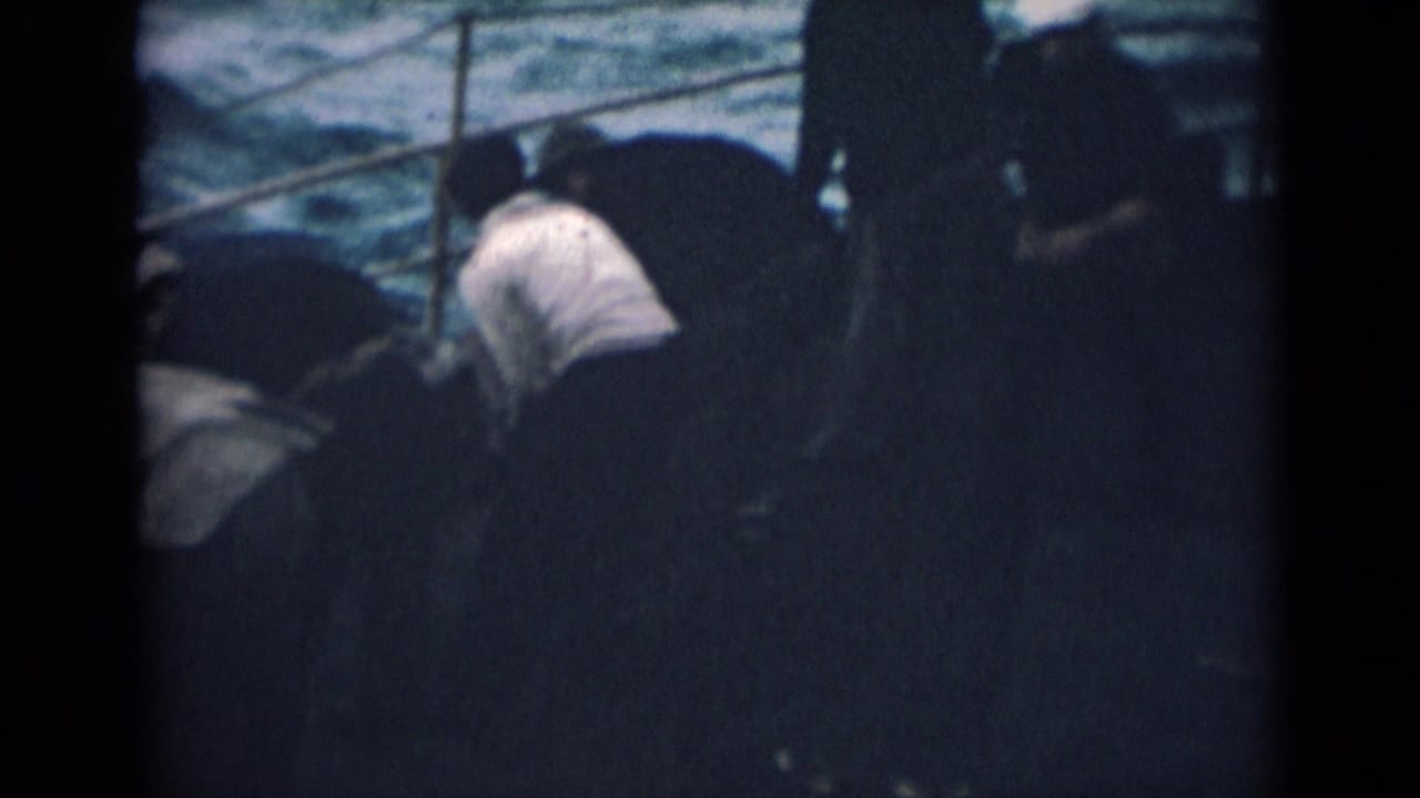 India 1946 8mm frame of men working on a boat deck, partly shadowed, with railings and rough water visible.