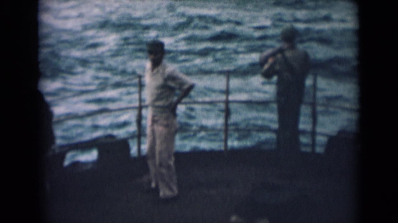 Two sailors stand near the ship railing with choppy water behind them.