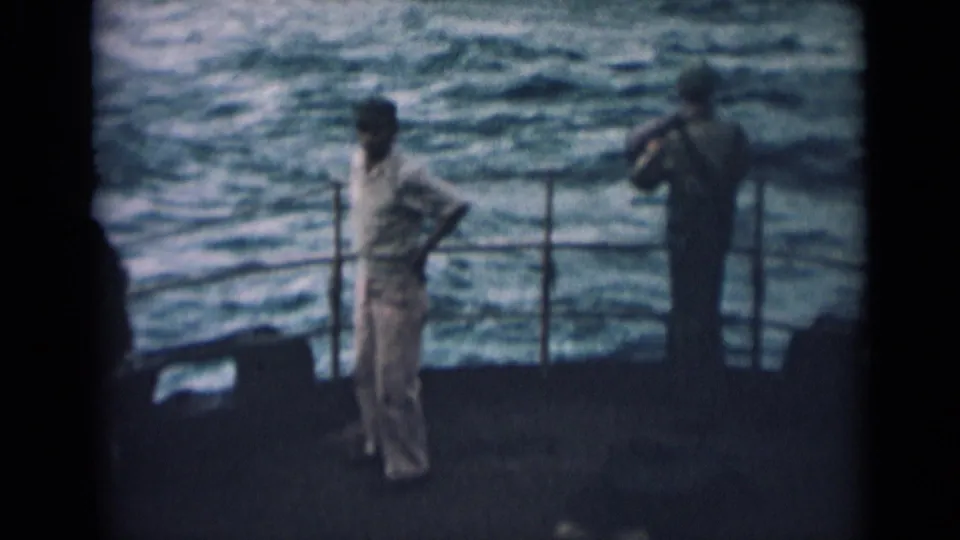 1946 India shipboard view of two sailors in pale uniforms standing near railings as water fills the background.