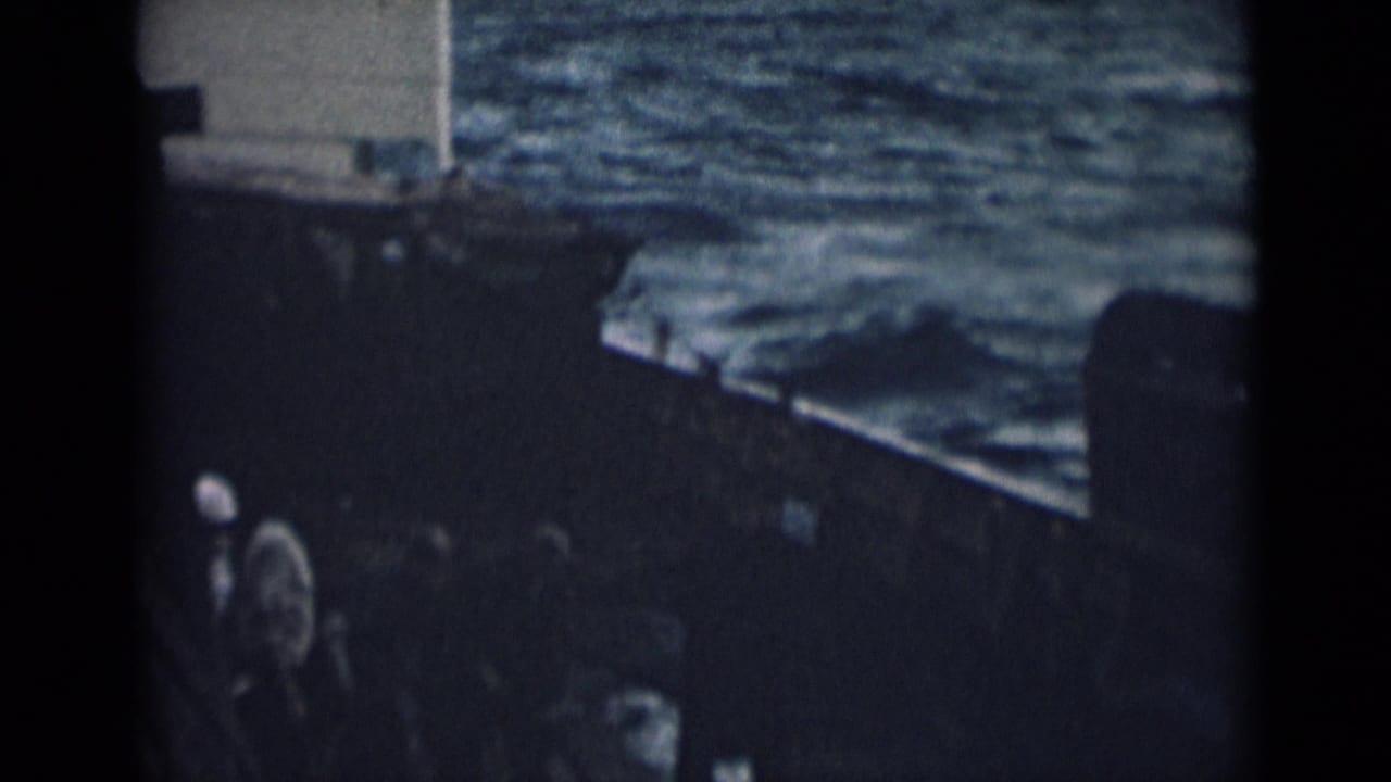 1946 India 8mm frame looking past a nearby boat edge toward rippled water and a partial vessel or dockside form.