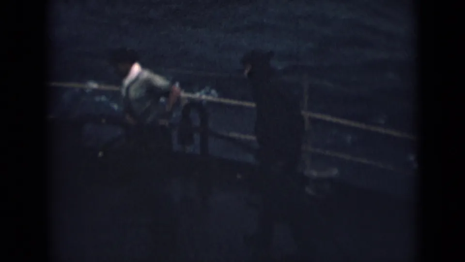 1946 shipboard frame from India showing a sailor working near the railing as water passes behind the vessel.