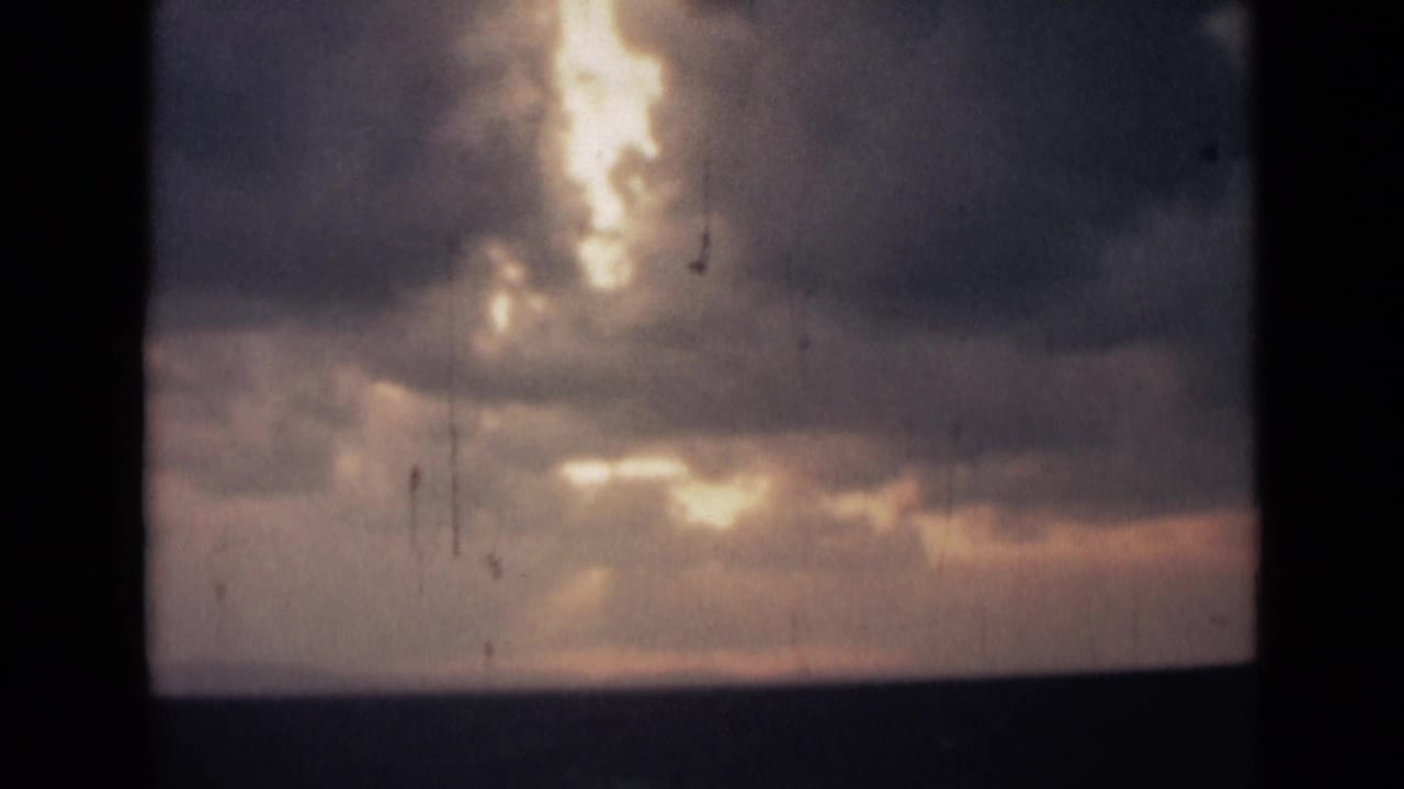 Cloudy sky with bright sunlight breaking through above a dark horizon.