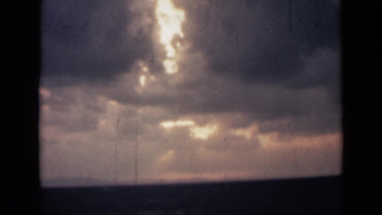 Cloud bank with bright openings of sunlight over a low dark horizon.