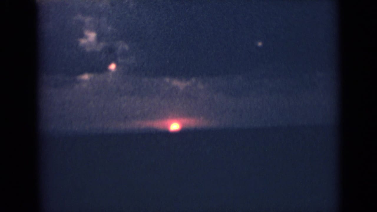 Dark horizon with a bright low sun or light beneath cloud cover.