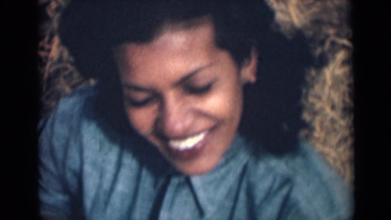 Smiling young woman in a blue shirt faces the camera in 1946 India-related 8mm home-movie footage.